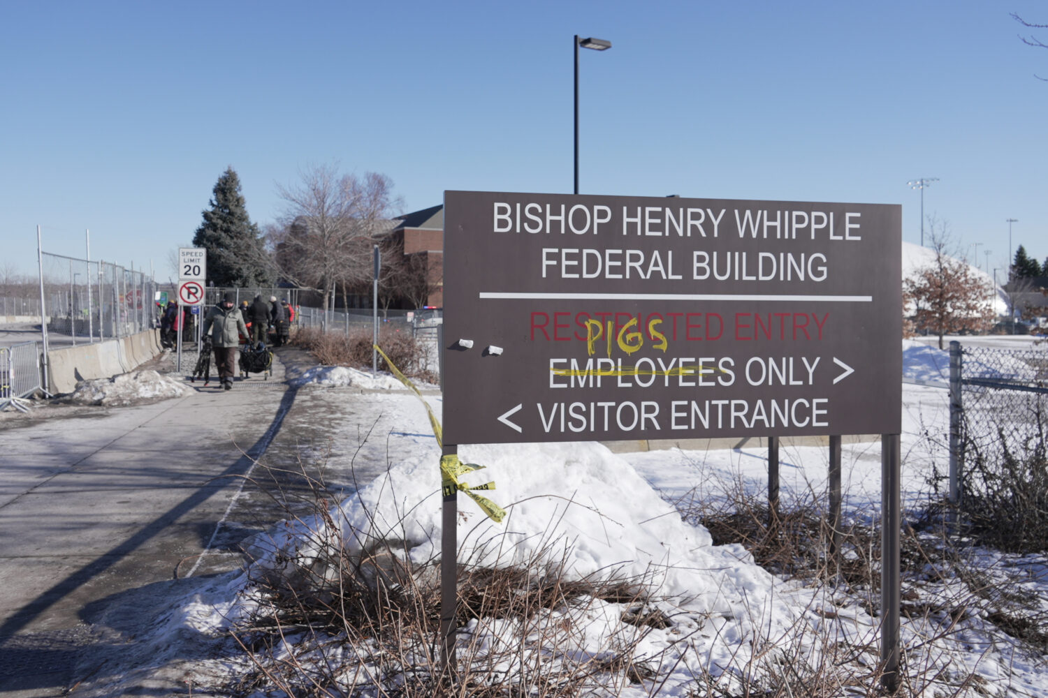 FILE - Protesters yell at cars coming and going near a defaced sign for Bishop Whipple Federal buil...