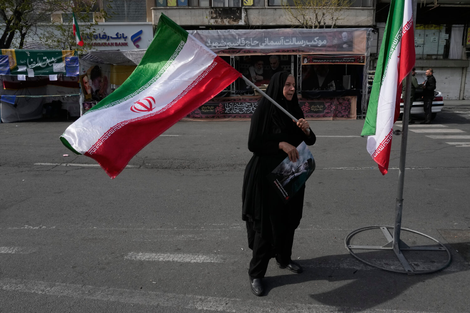 A woman waves an Iranian flag during a campaign in support of the government at the Enqelab-e-Eslam...