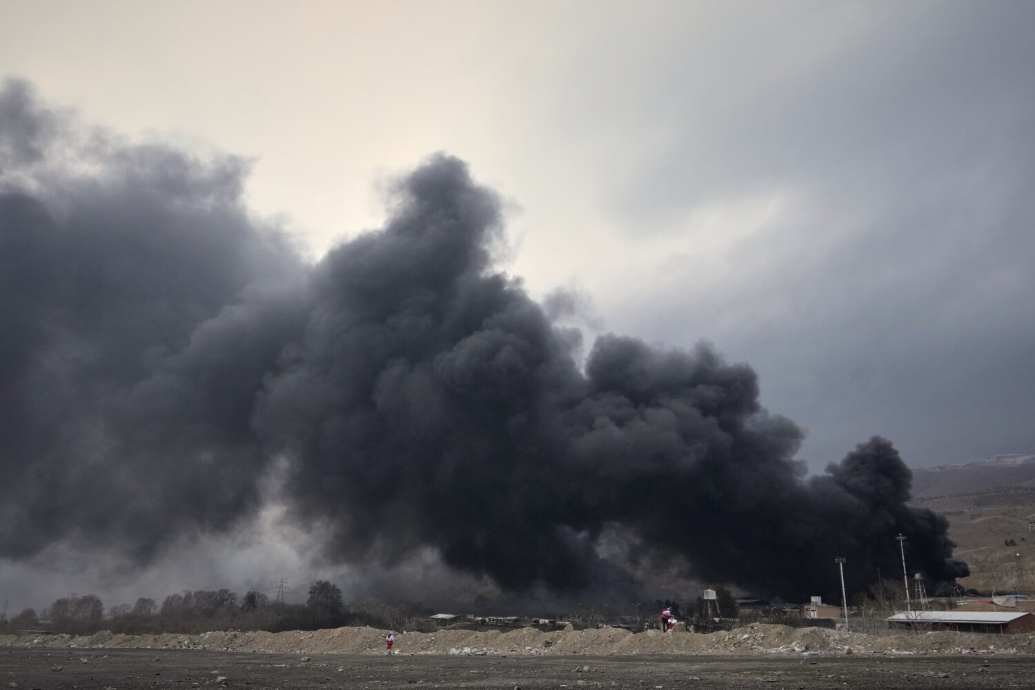 A thick plume of smoke rises from an oil storage facility hit by a U.S.-Israeli strike late Saturda...