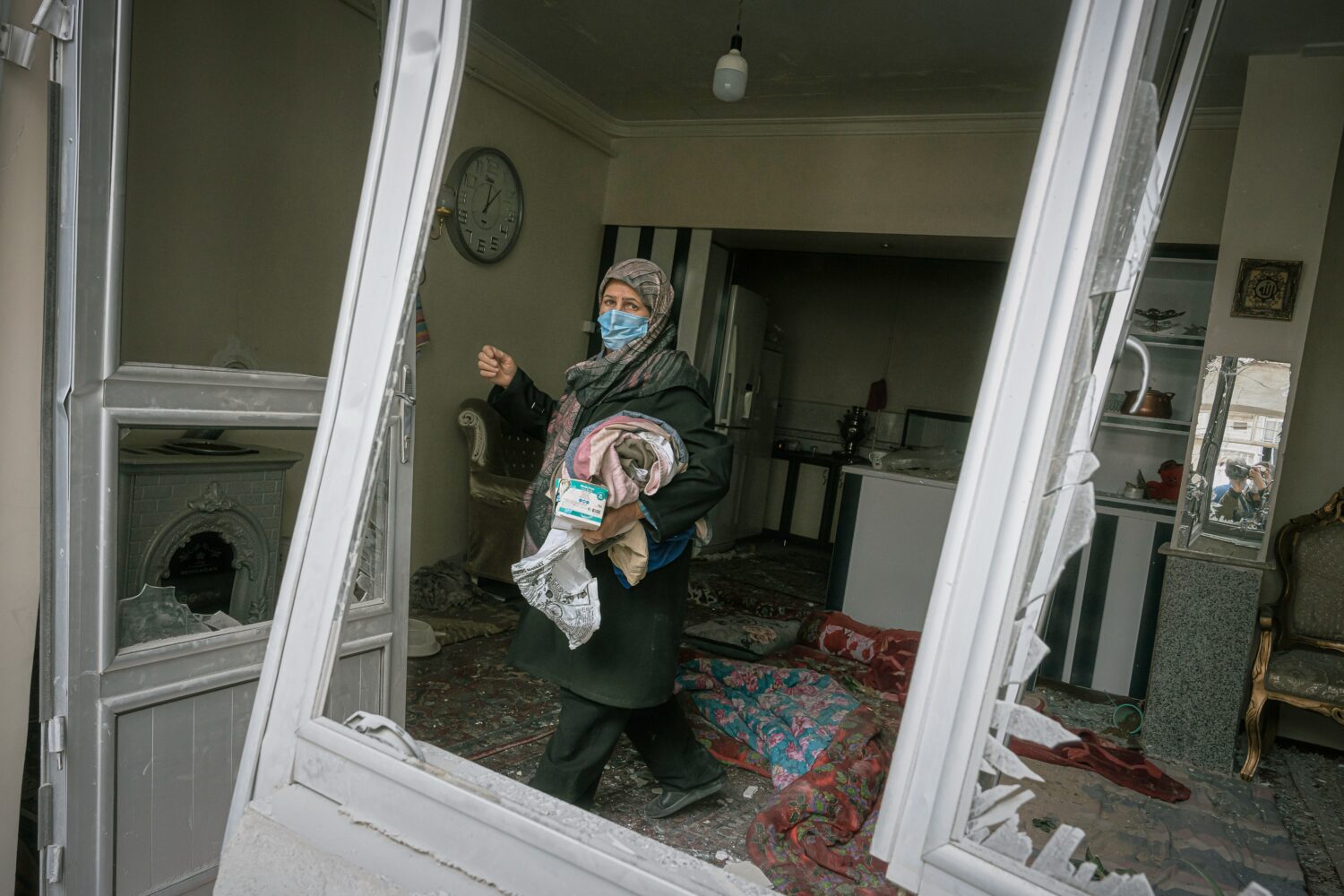 A woman collects belongings from a house damaged when a nearby residential building was hit in an o...