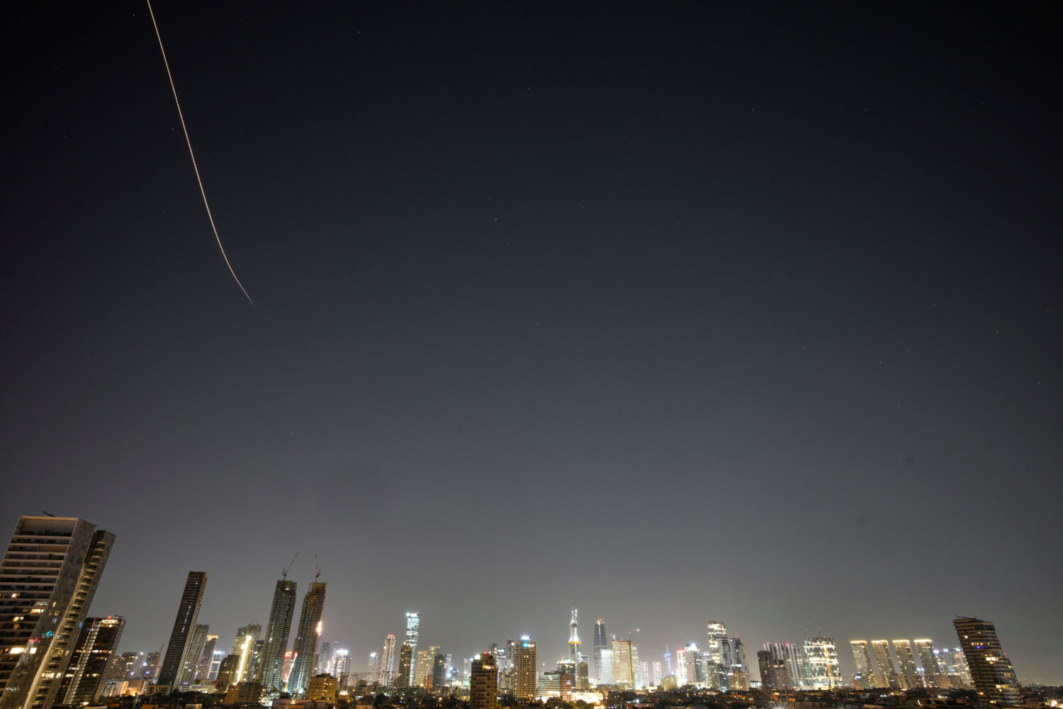 Missiles launched from Iran streak across the sky over central Israel, early Tuesday, March 24, 202...