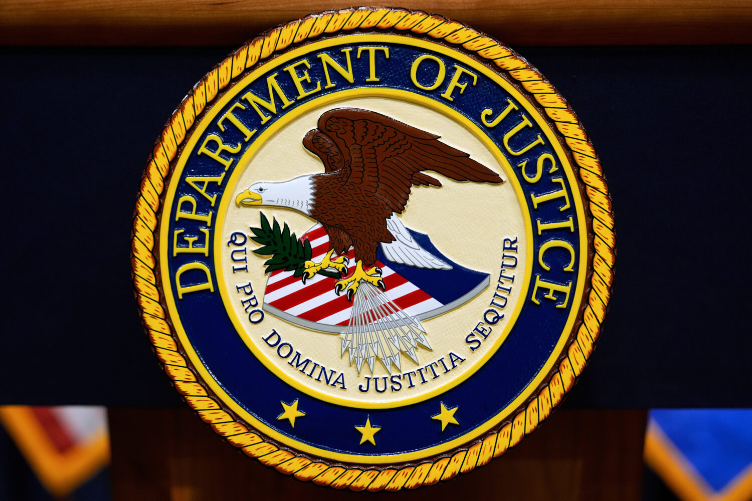 FILE - The U.S. Department of Justice logo is seen on a podium before a press conference, May 6, 20...