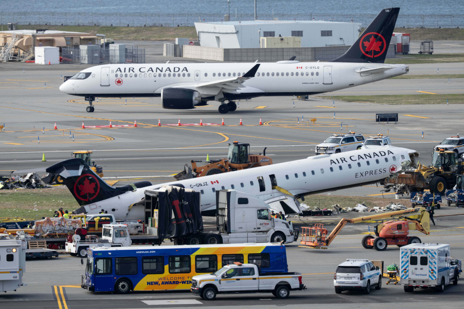 An Air Canada Express jet taxis past the wreckage of an Air Canada Express jet, Wednesday, March 25...