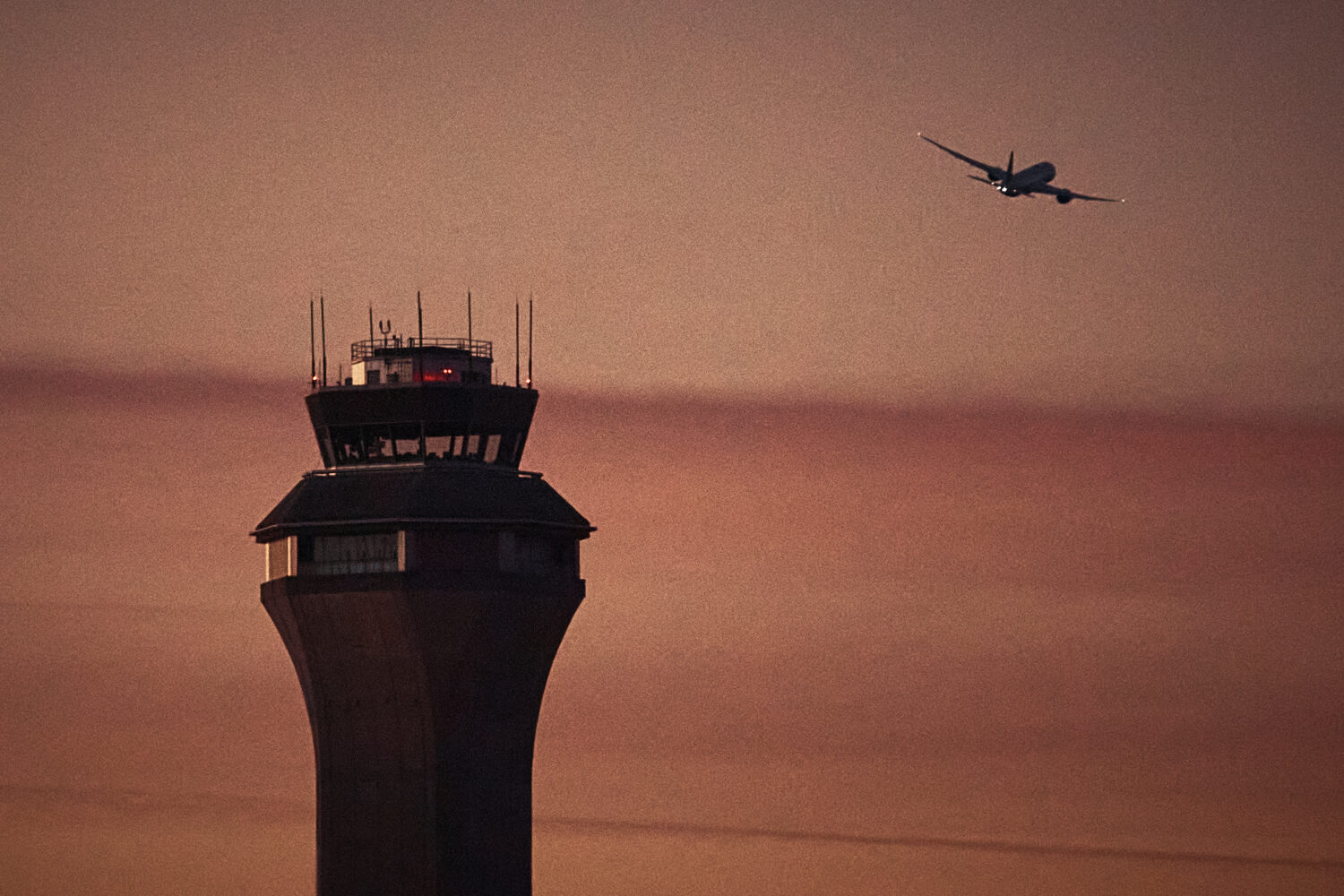 FILE - A plane flies by a control tower at Newark Liberty International Airport on Nov. 7, 2025, in...