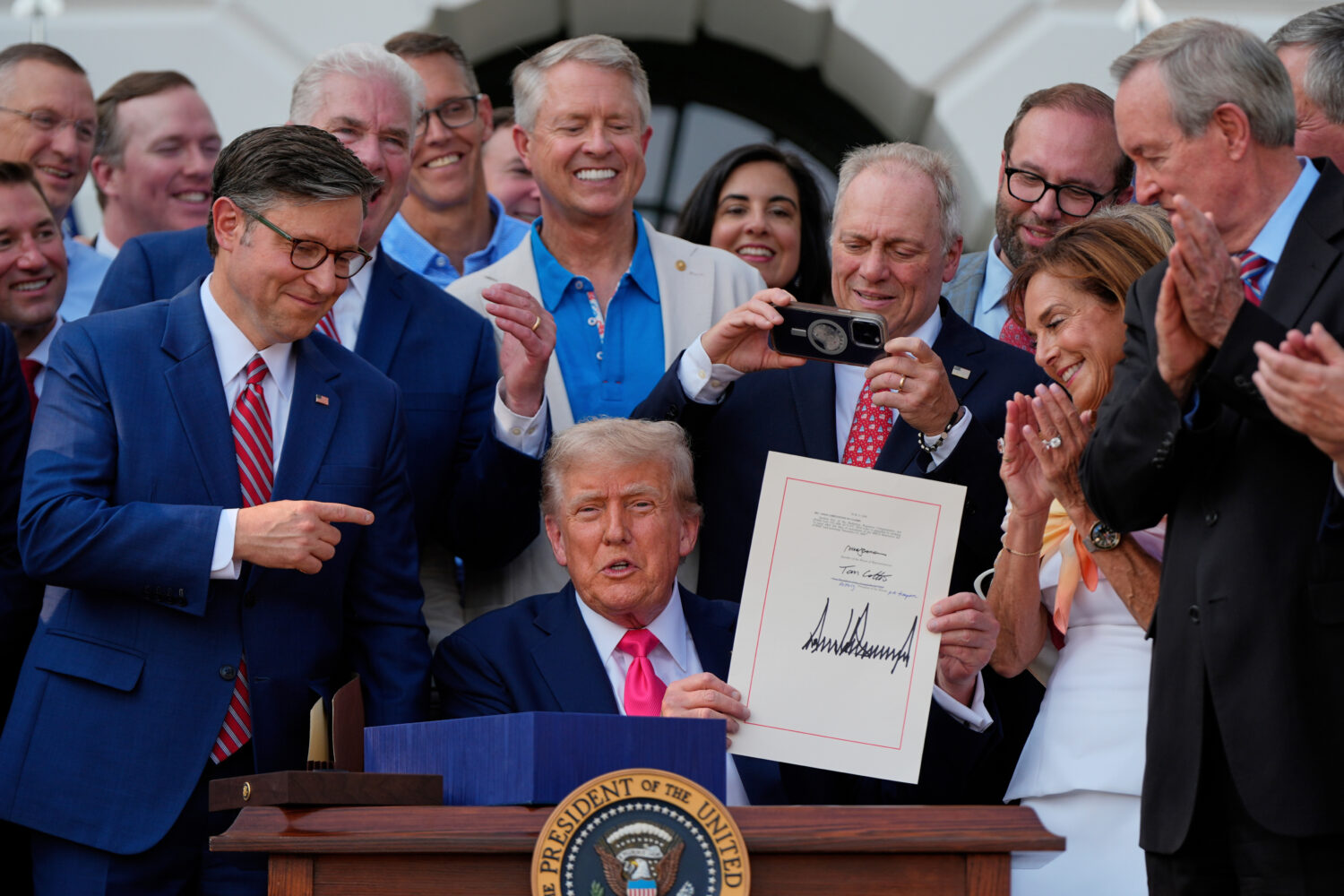 FILE - President Donald Trump holds his signed signature bill of tax breaks and spending cuts at th...