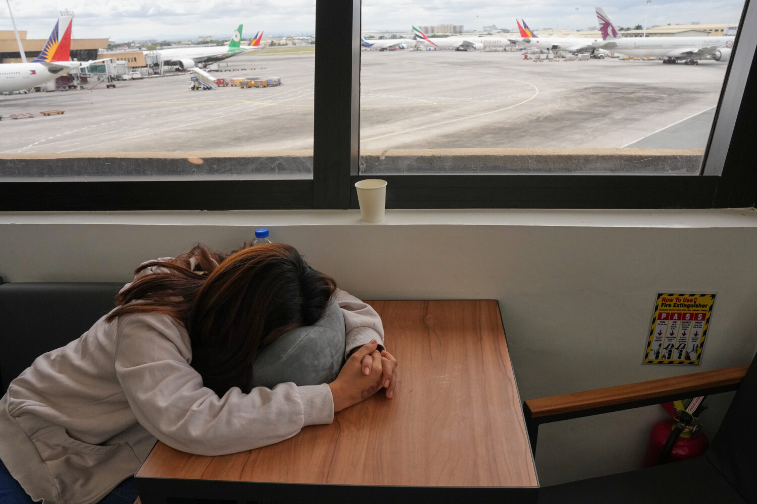 An overseas Filipino worker sleeps as she waits for updates on her cancelled flight to the Middle E...