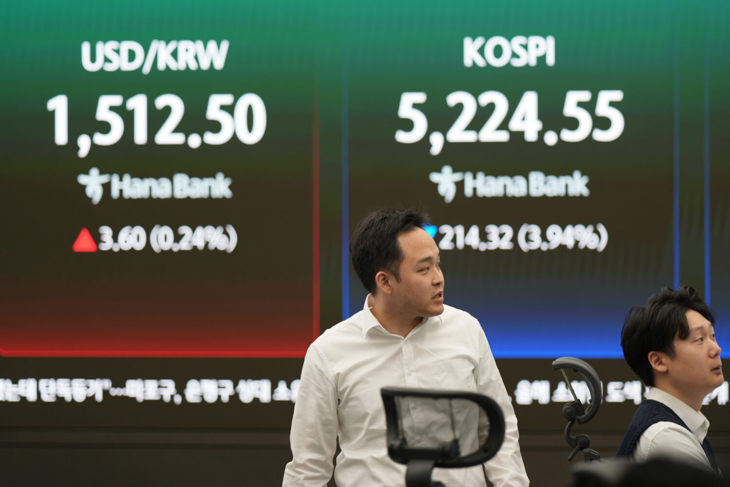 Dealers work near the screens showing the Korea Composite Stock Price Index (KOSPI), right, and the...