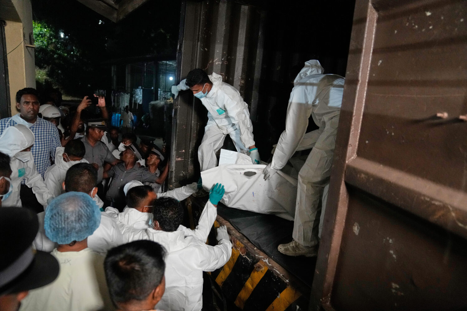 Healthcare workers unload from a vehicle, the bodies of Iranian sailors who died when their IRIS De...