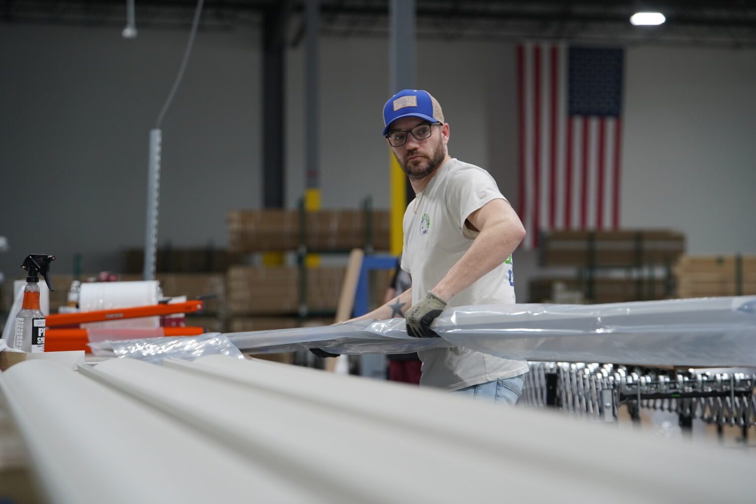 A worker lifts an aluminum beam on the factory floor at The Luxury Pergola, a company that manufact...
