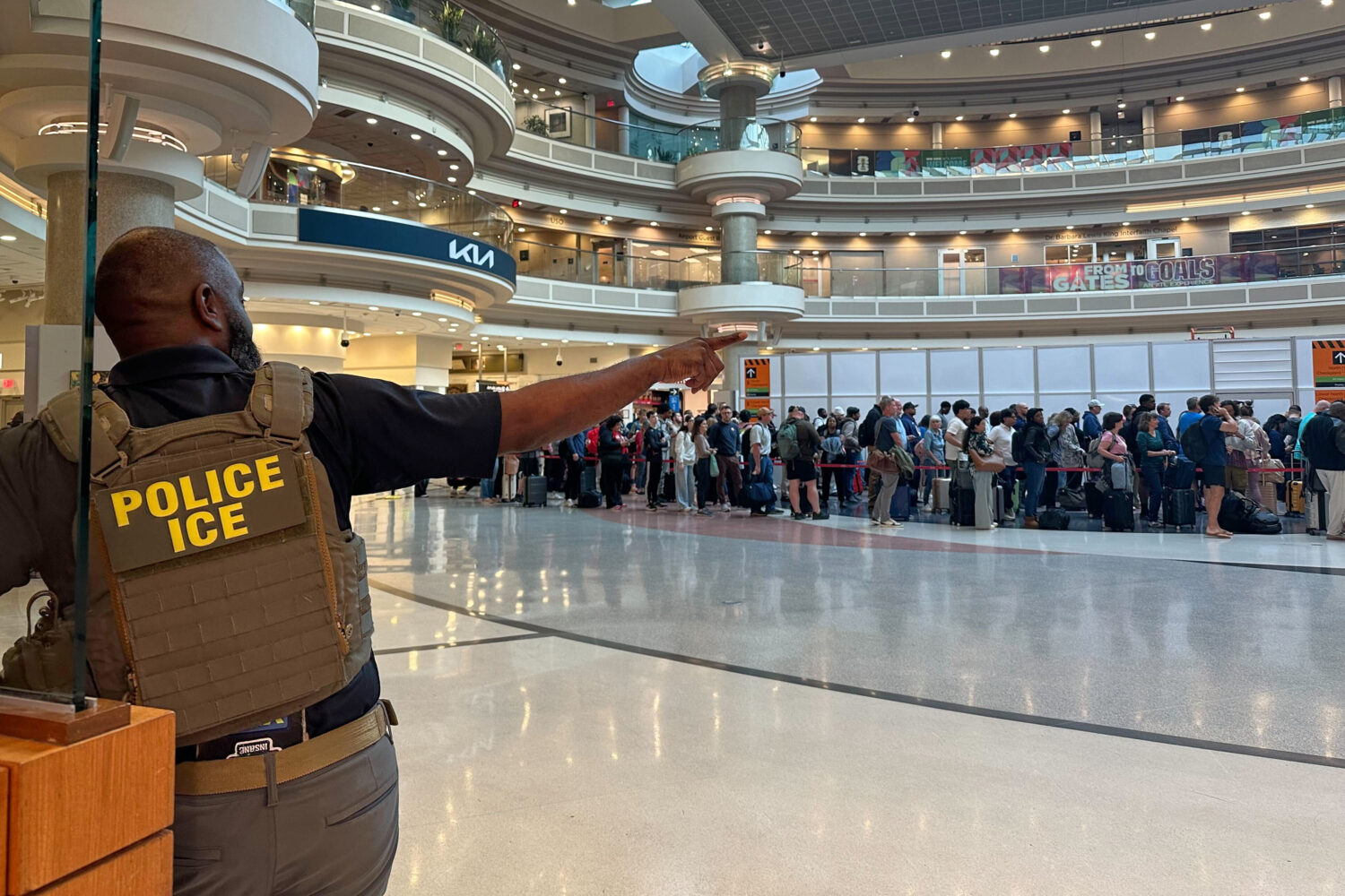 A federal immigration agent is seen as people wait in a TSA line at the Hartsfield-Jackson Atlanta ...