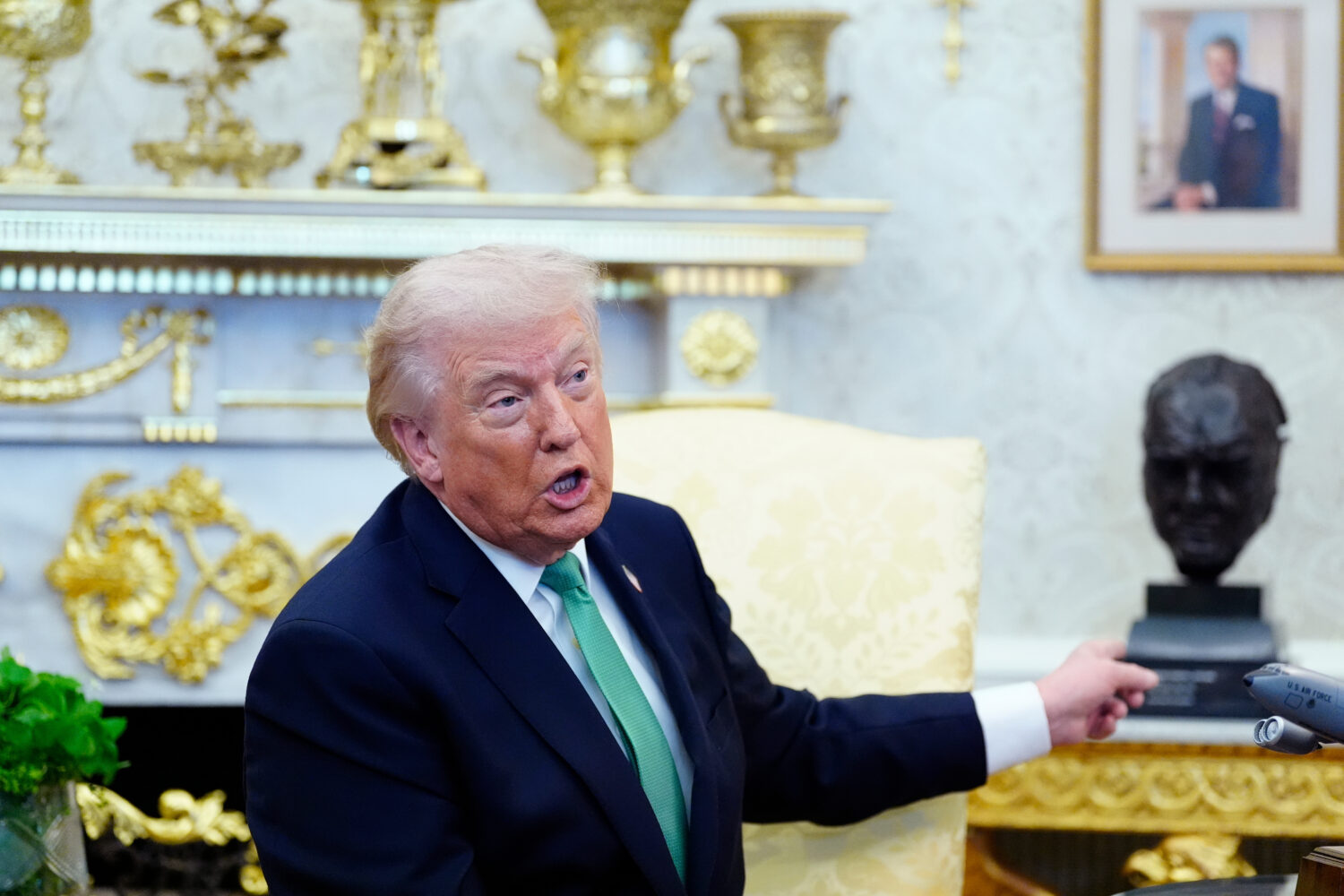 President Donald Trump points to a bust of Winston Churchill as he speaks during a meeting with Iri...
