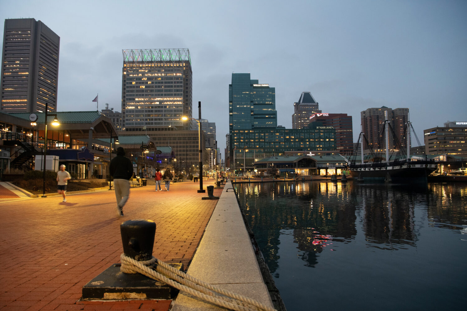 People walk around Baltimore's Inner Harbor on March 5, 2026. (AP Photo/Michael Phillis)Credit: ASS...