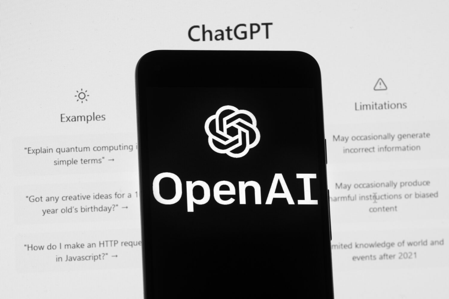 FILE - The OpenAI logo is seen on a mobile phone in front of a computer screen which displays the C...
