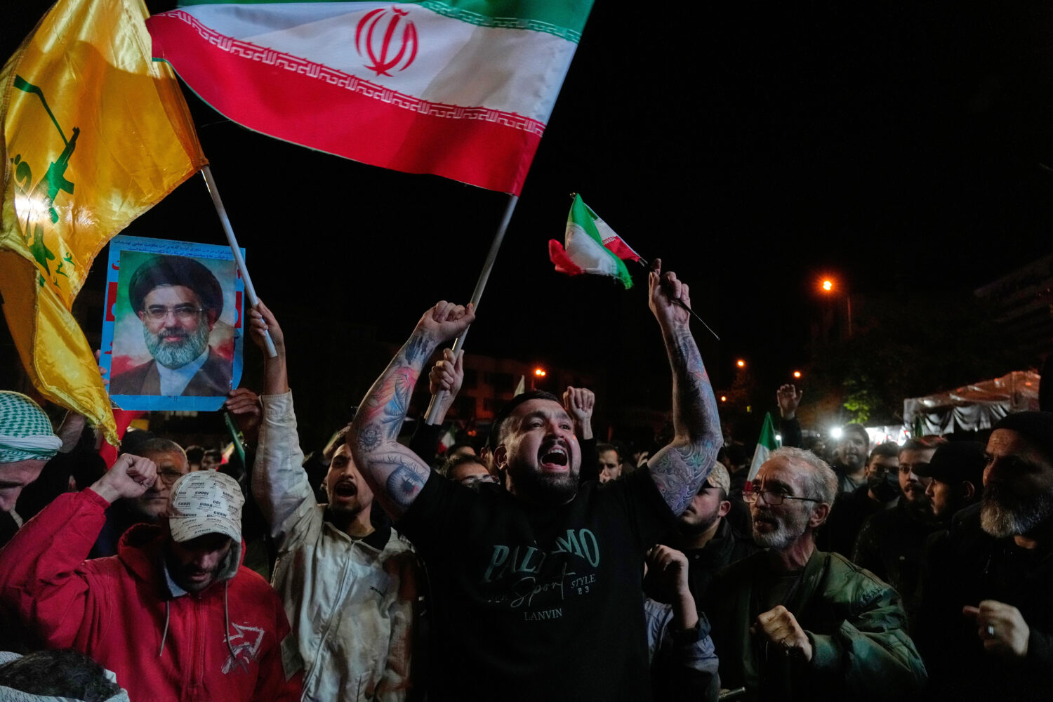 Pro-government demonstrators chant slogans as they hold Iranian flags and a poster of the Supreme L...