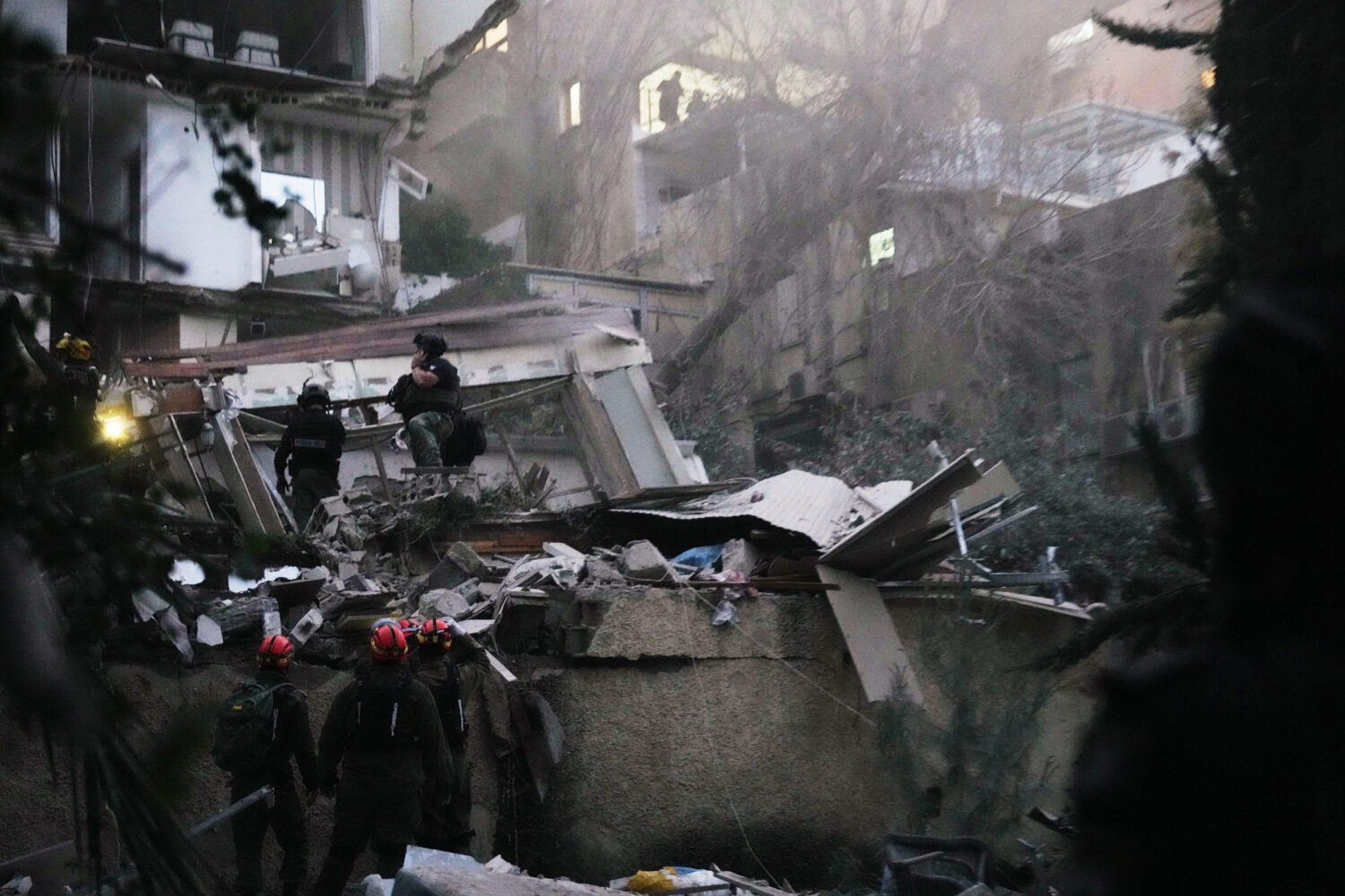 Israeli security forces and rescue teams work amid the rubble of a residential building struck by a...