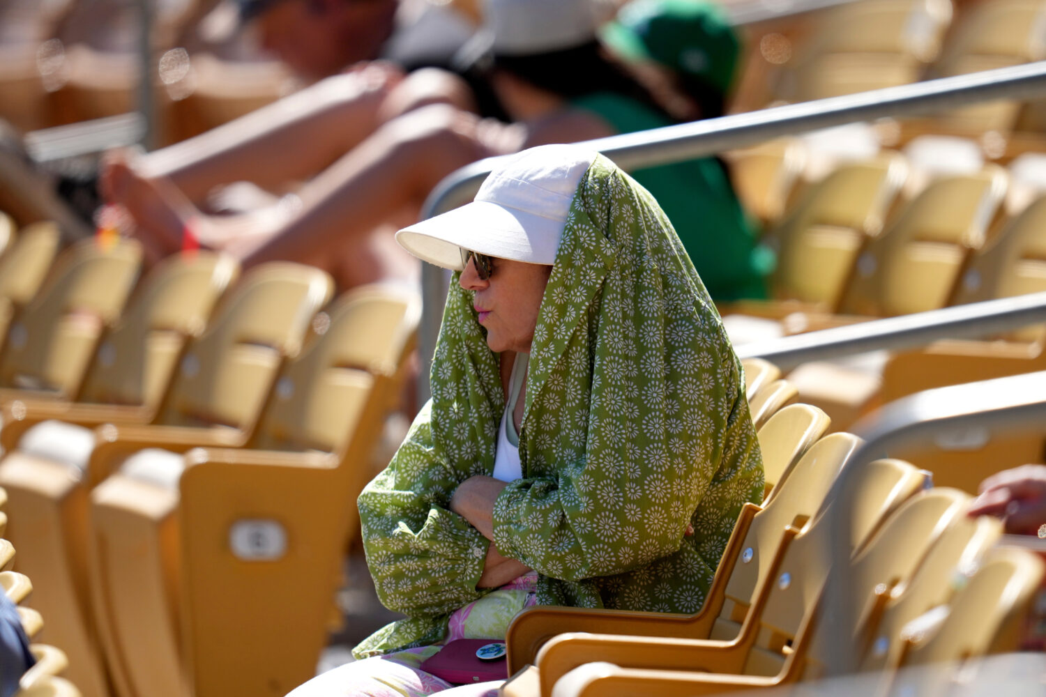 FILE - A baseball fan tries to shield from the sun during the fourth inning of a spring training ba...