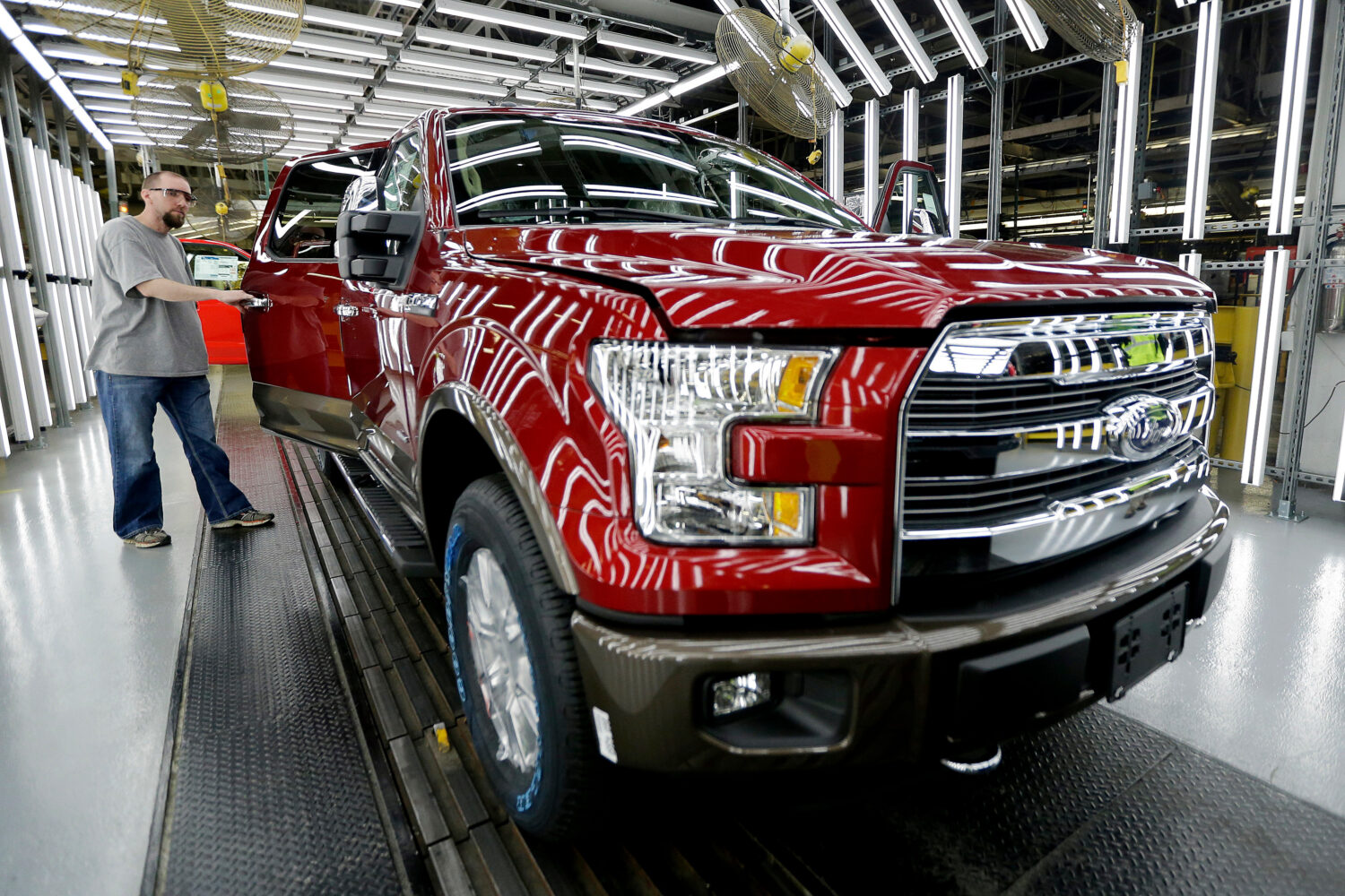 FILE - A worker inspects a new aluminum-alloy body Ford F-150 truck at the company's Kansas City As...