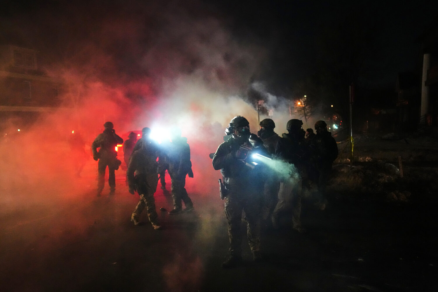 FILE - Law enforcement officers stand amid tear gas at the scene of a reported shooting, Jan. 14, 2...
