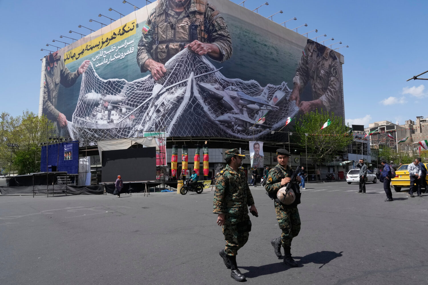FILE - Two police officers walk in front of an anti-U.S. billboard depicting American aircraft bein...