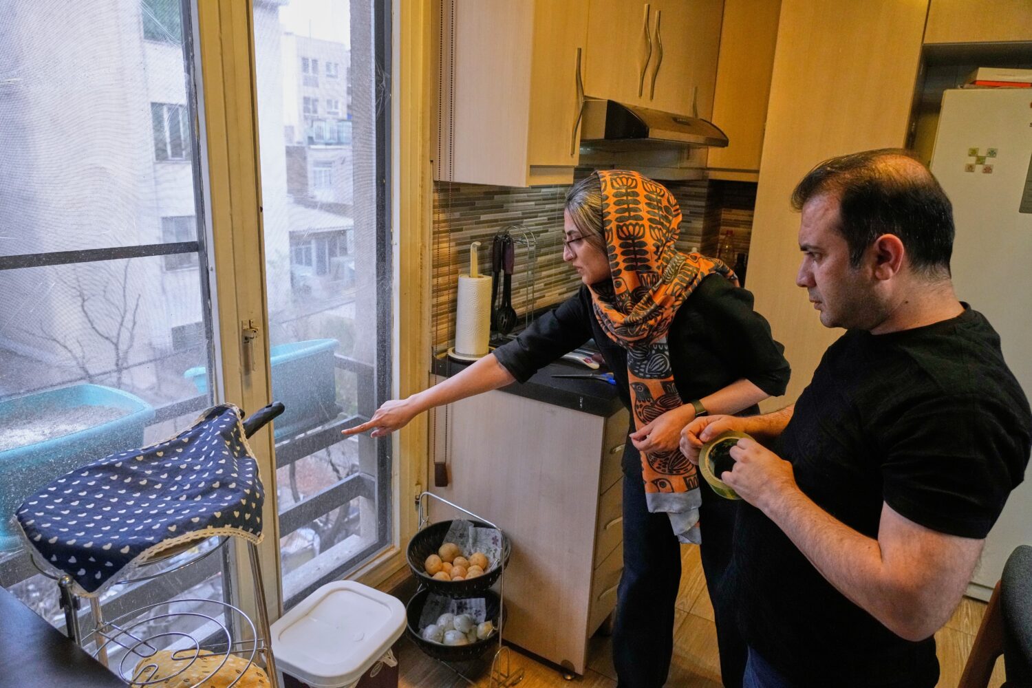 Zahra Arghavan, left, and Mehdi Alishir check one of the windows at their home in Tehran, Iran, Sun...