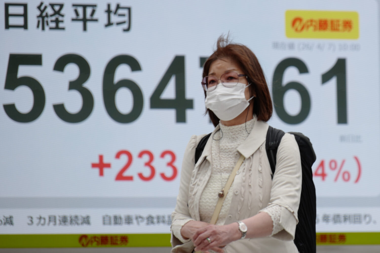 A person walks in front of an electronic stock board showing Japan's Nikkei index at a securities f...