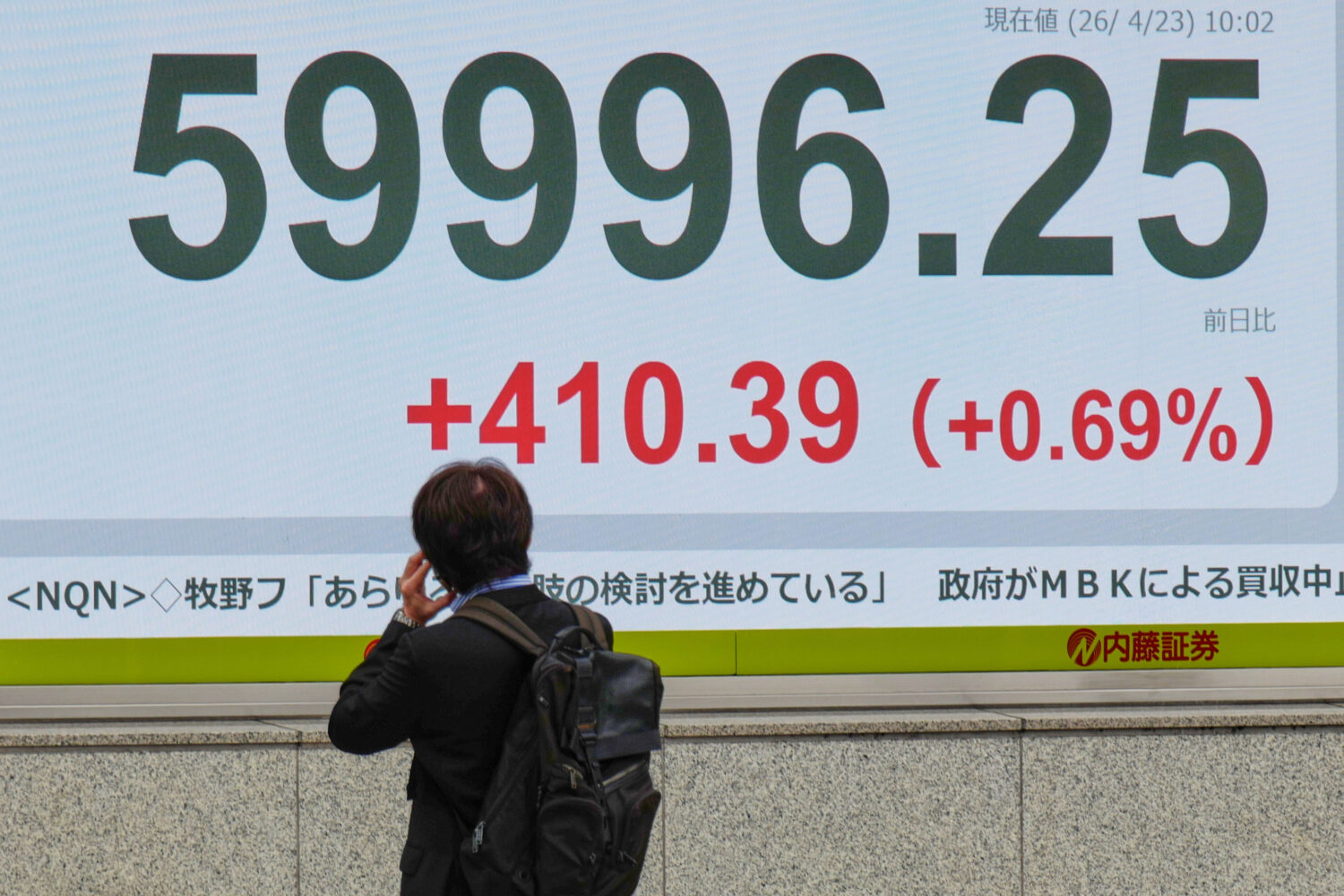 A person looks at an electronic stock board showing Japan's Nikkei index at a securities firm Thurs...