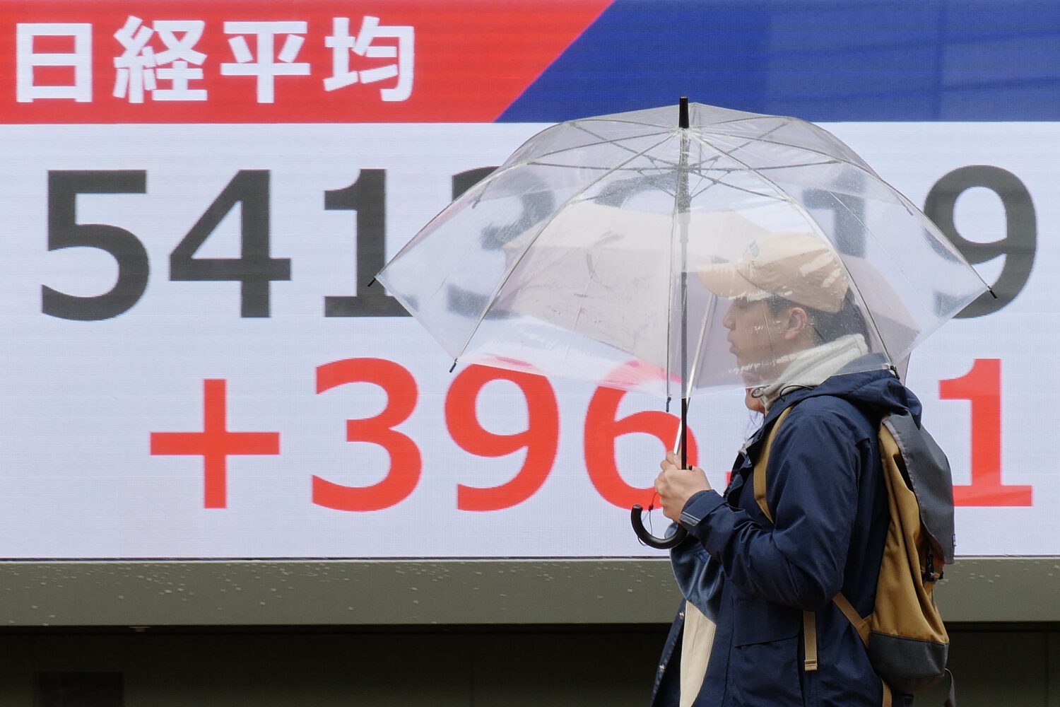 Persons walk in front of an electronic stock board showing Japan's Nikkei index at a securities fir...