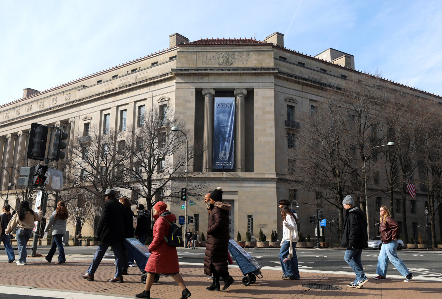 FILE - Tourists walk past a banner with President Donald Trump hanging on the Department of Justice...