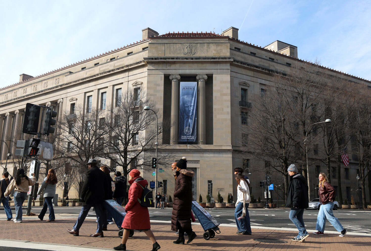 FILE - Tourists walk past a banner with President Donald Trump hanging on the Department of Justice...