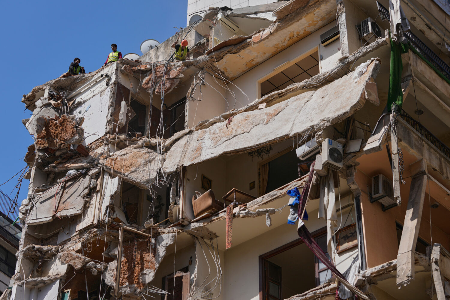 Workers remove the rubble as rescuers keep searching for a missing woman and girl at a destroyed bu...