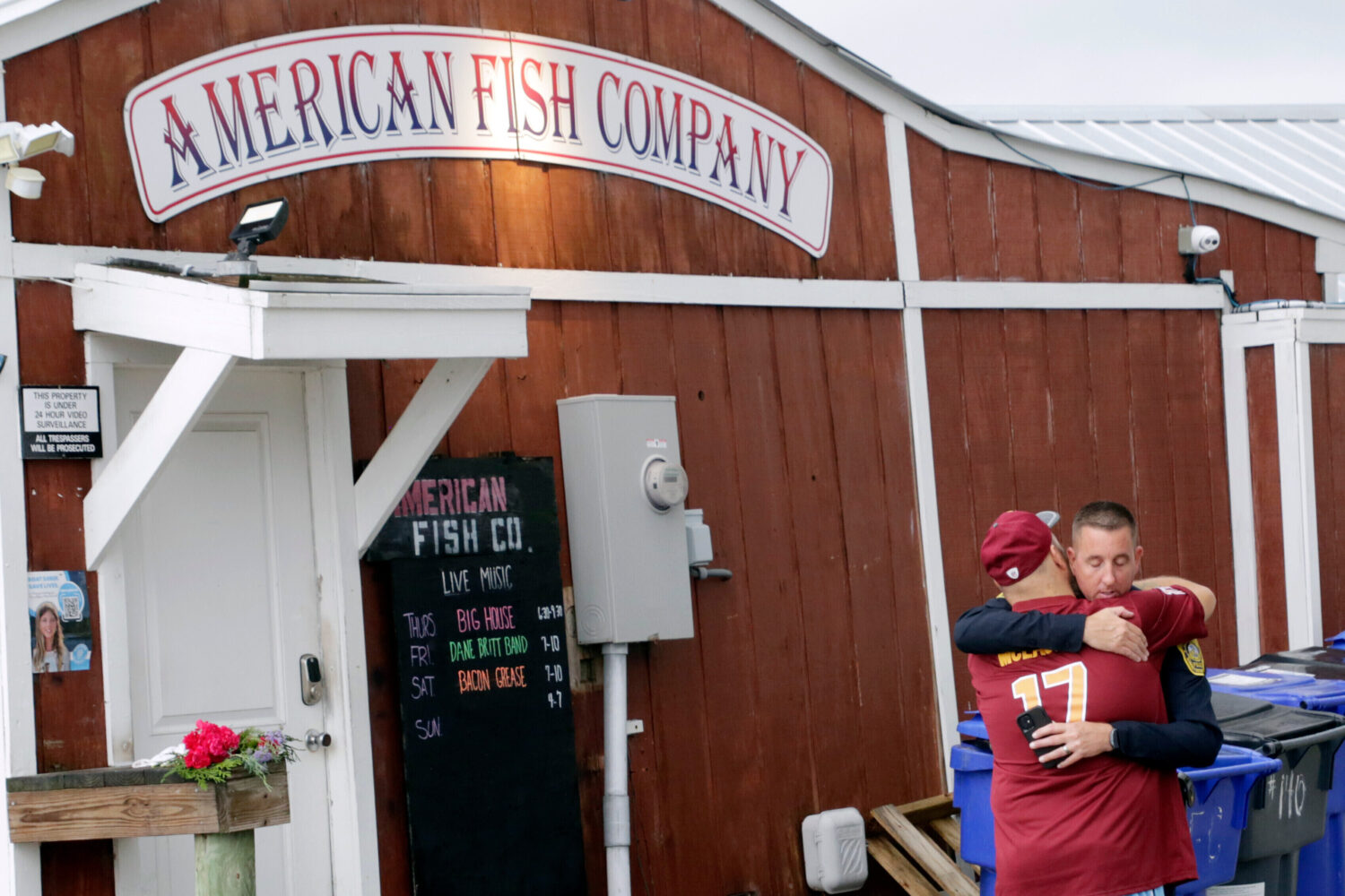 FILE - A man hugs a police officer in front of the American Fish Company following a fatal shooting...
