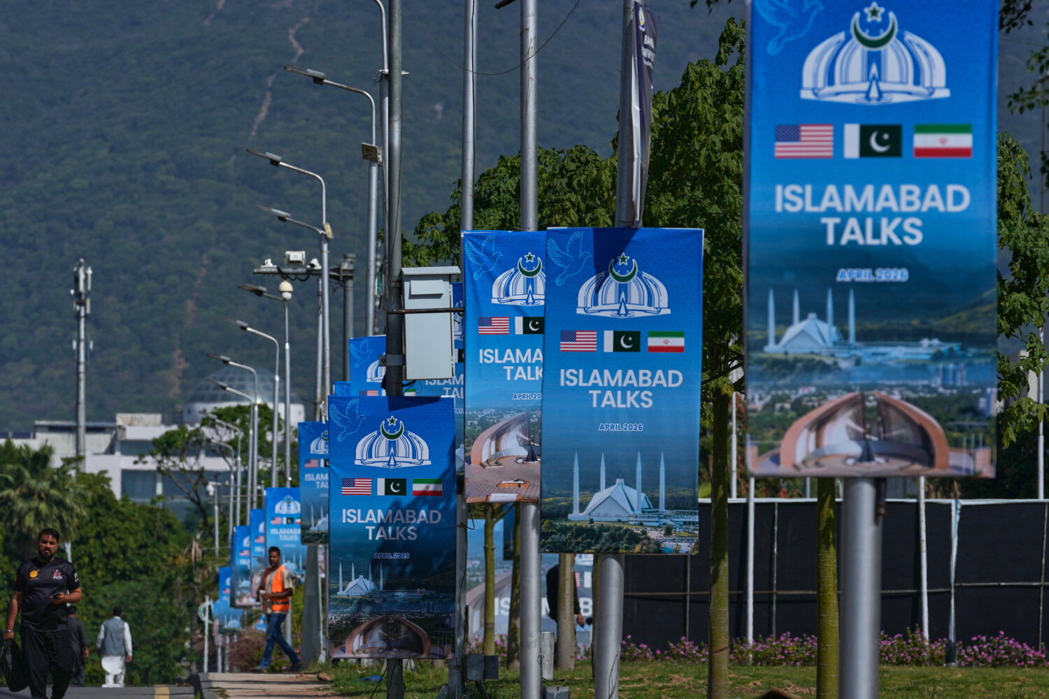 Workers walk past billboards near the Serena Hotel ahead of the second round of negotiations betwee...