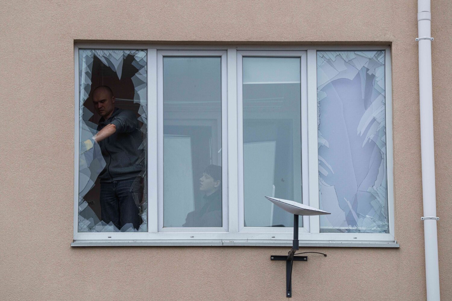 People remove broken glass from their windows after a Russian strike on residential neighbourhood i...