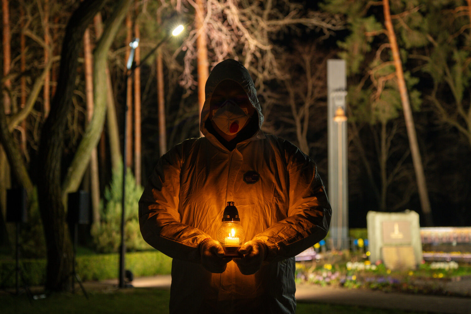 A man dressed in white protective suits holds a candle during a memorial service dedicated to firef...