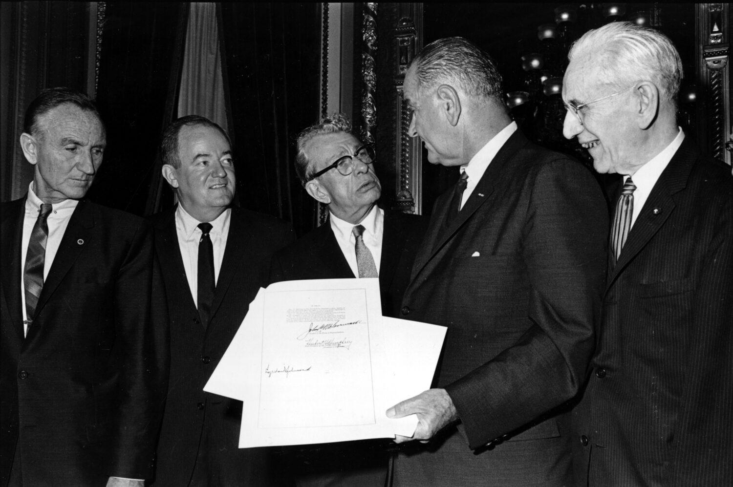 FILE - President Lyndon B. Johnson holds the signed document of the Voting Rights Act of 1965 as he...