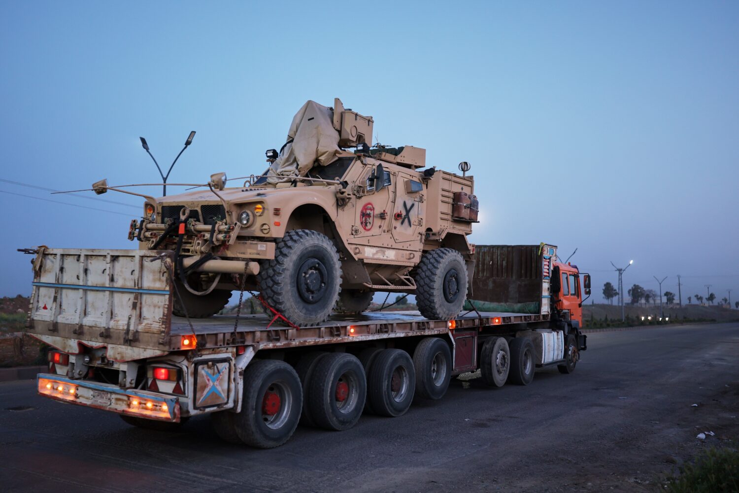 A U.S. military vehicle is transported on a truck as part of a convoy withdrawing from Qasrak base ...