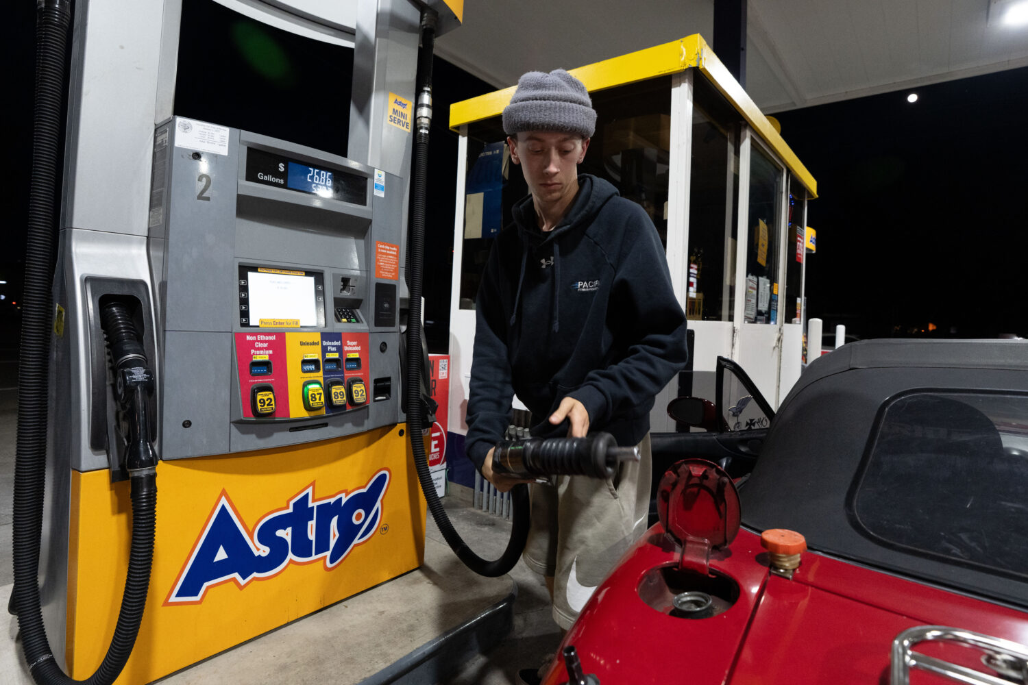 Luciano V. replaces the fuel nozzel after filling the tank of their 1999 Mazda Miata at an Astro ga...
