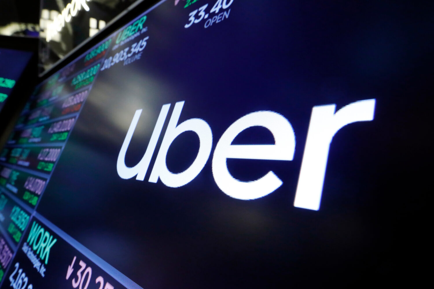 FILE - The Uber logo appears above a trading post on the floor of the New York Stock Exchange, Aug....