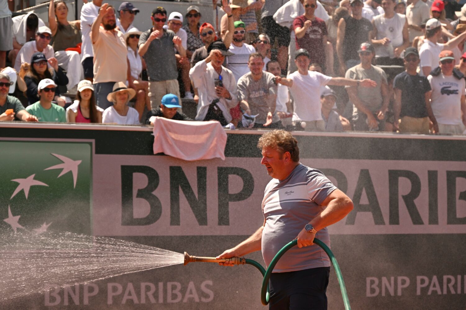 Spectators react as stadium worker sprays the court with water during the second round men's single...