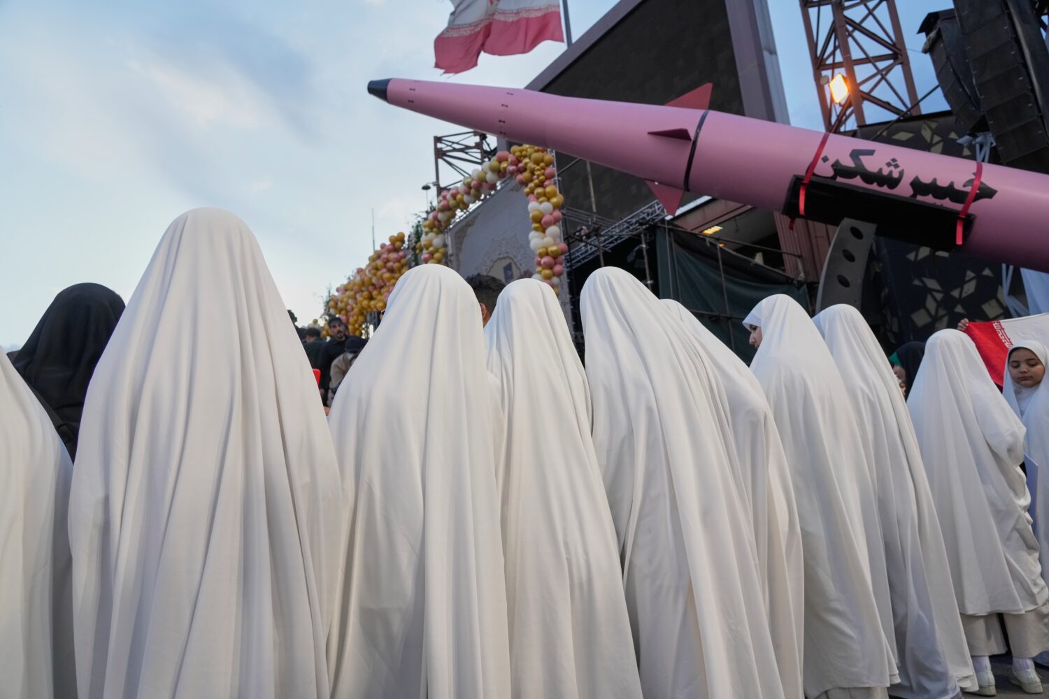 A group of girls stand beside a "Khaybar-buster" missile during a mass wedding ceremony for couples...