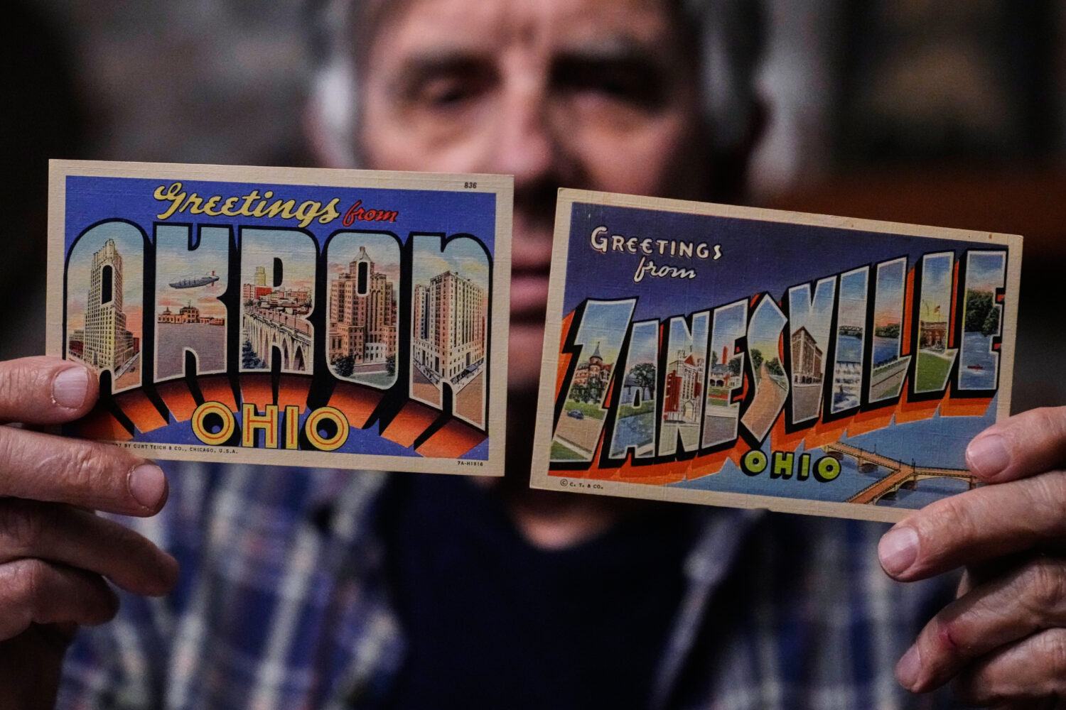 Postcard collector Peter Meggison, holds up two examples of large letter postcards from places acro...