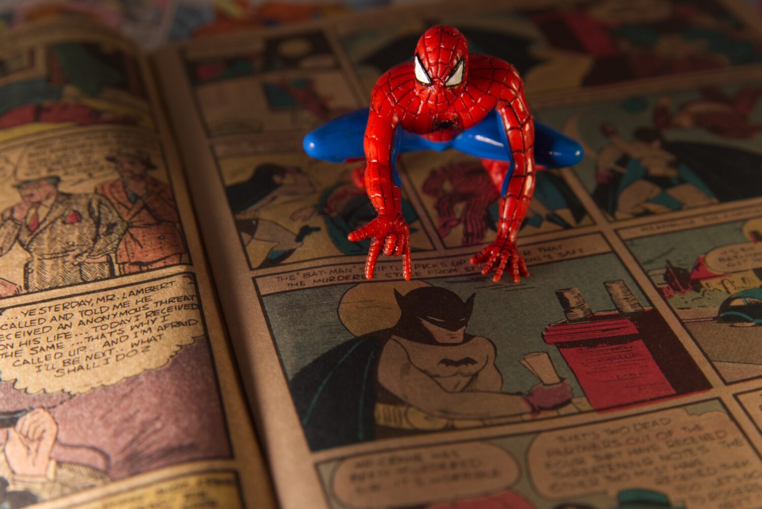 A Spiderman figurine sits atop a facsimile copy of the May 1939 Detective Comics anthology series i...