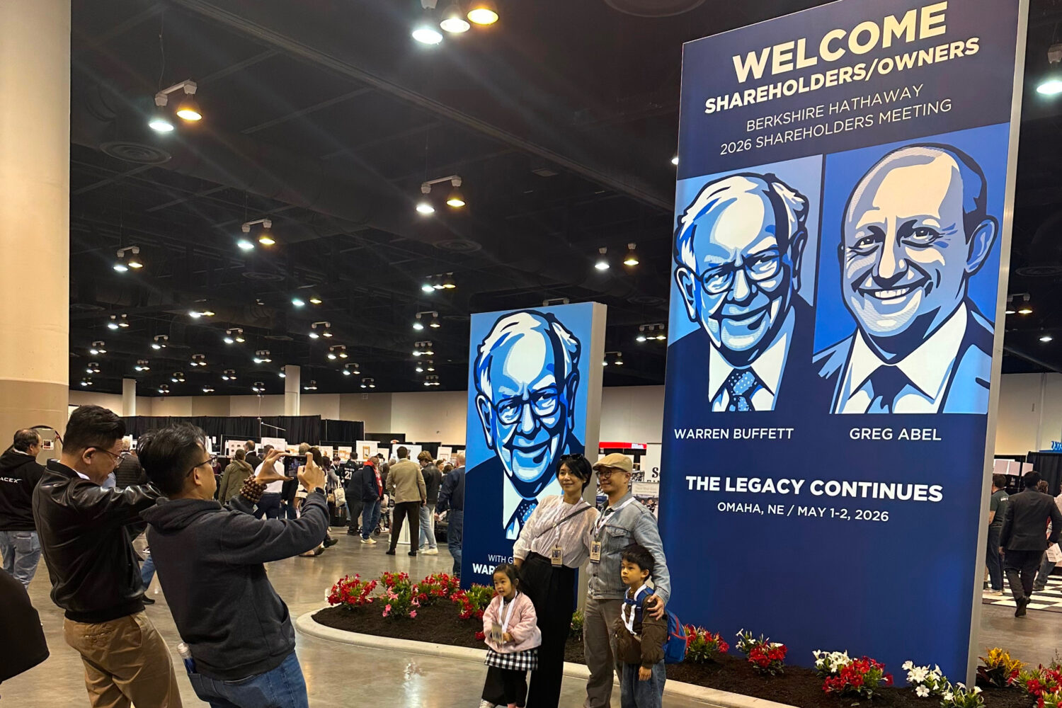 Shareholders line up to take pictures with depictions of Berkshire Hathaway's new CEO Greg Abel and...