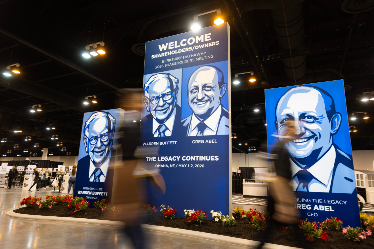 People walk past large portraits of Berkshire Hathaway's Warren Buffett, left, and CEO Greg Abel in...