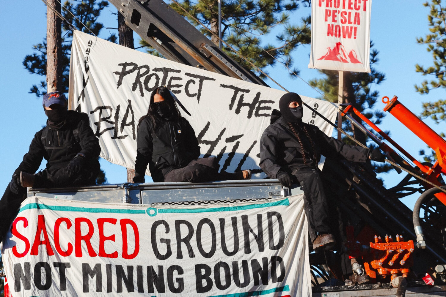 Masked demonstrators sit atop drilling equipment on Thursday, April 30, 2026, in Pennington County,...