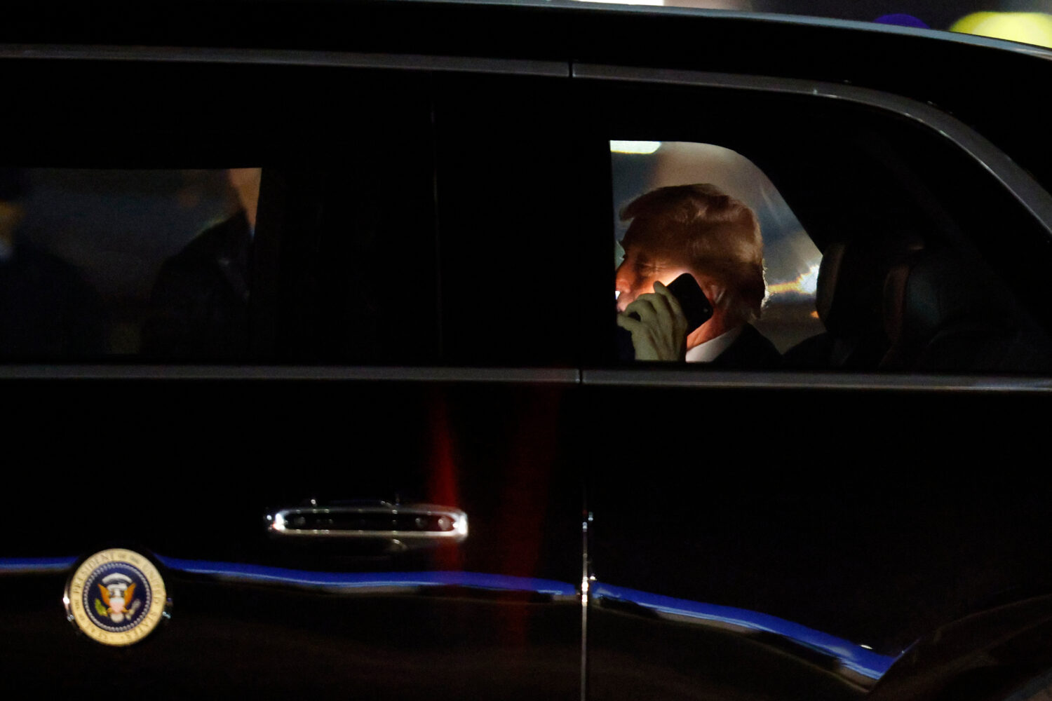 FILE - President Donald Trump talks on his cell phone in his limousine, known as "The Beast," upon ...