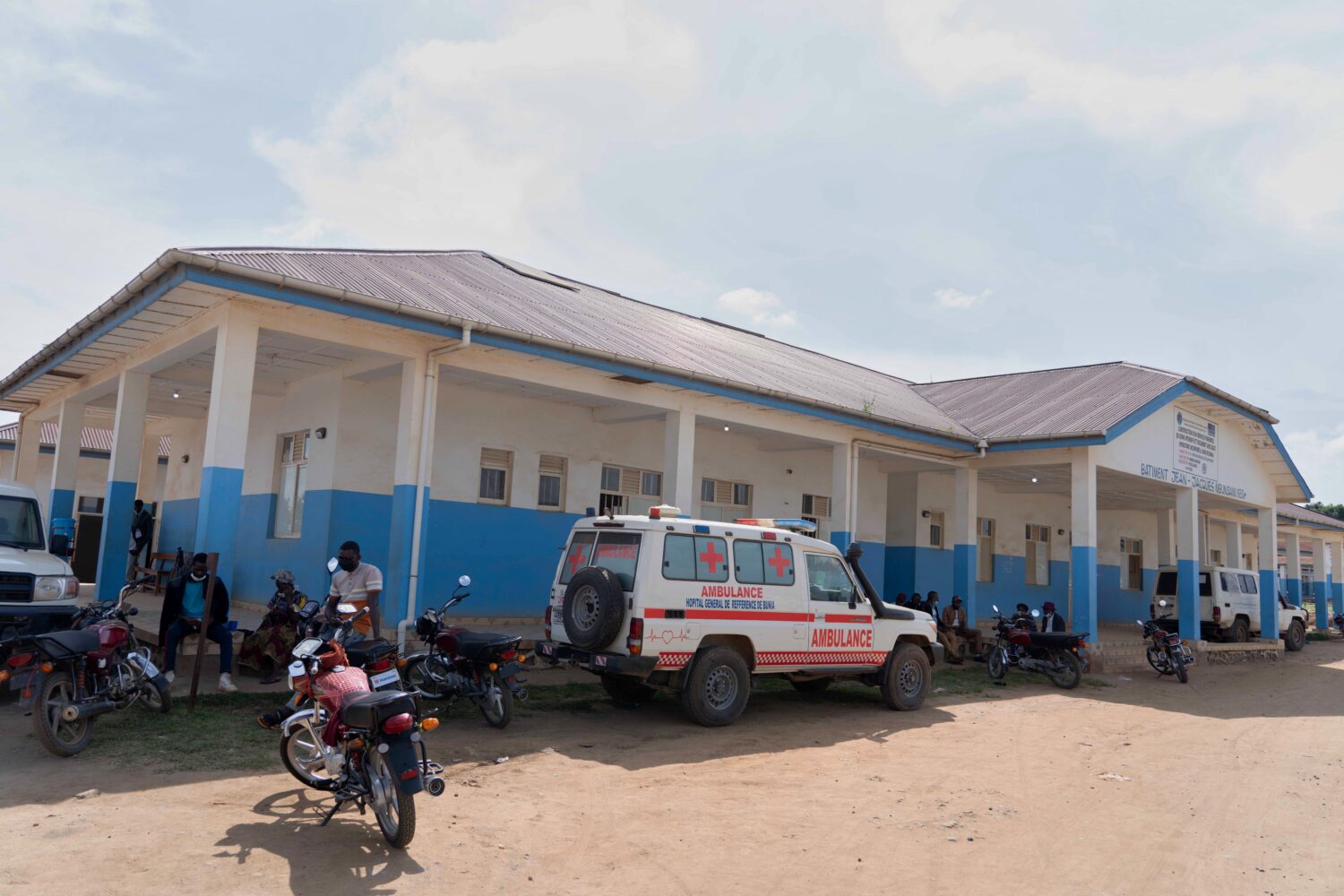 People wait near an ambulance at a hospital in Bunia, Congo, Sunday, May 17, 2026. (AP Photo/ Dirol...