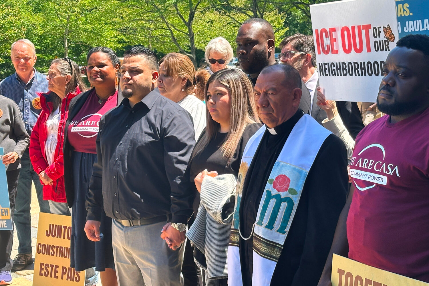 Kilmar Abrego Garcia and his wife, center, hold hands as people rally in support of him at a news c...