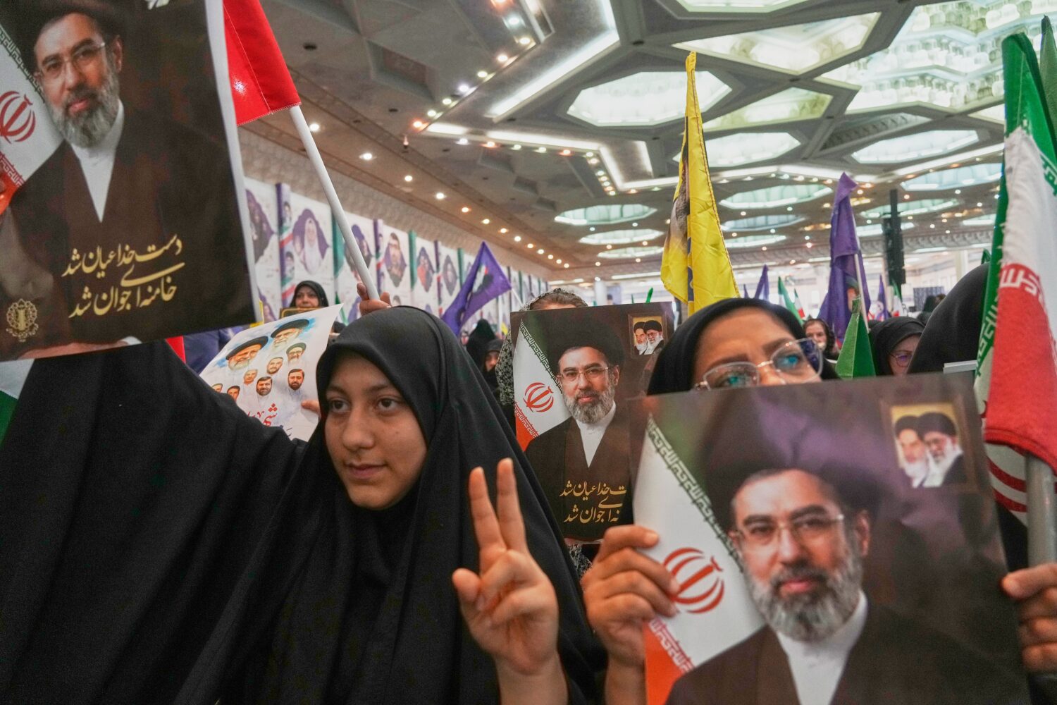 Women hold portraits of Iran's Supreme Leader, Ayatollah Mojtaba Khamenei, during a ceremony honori...