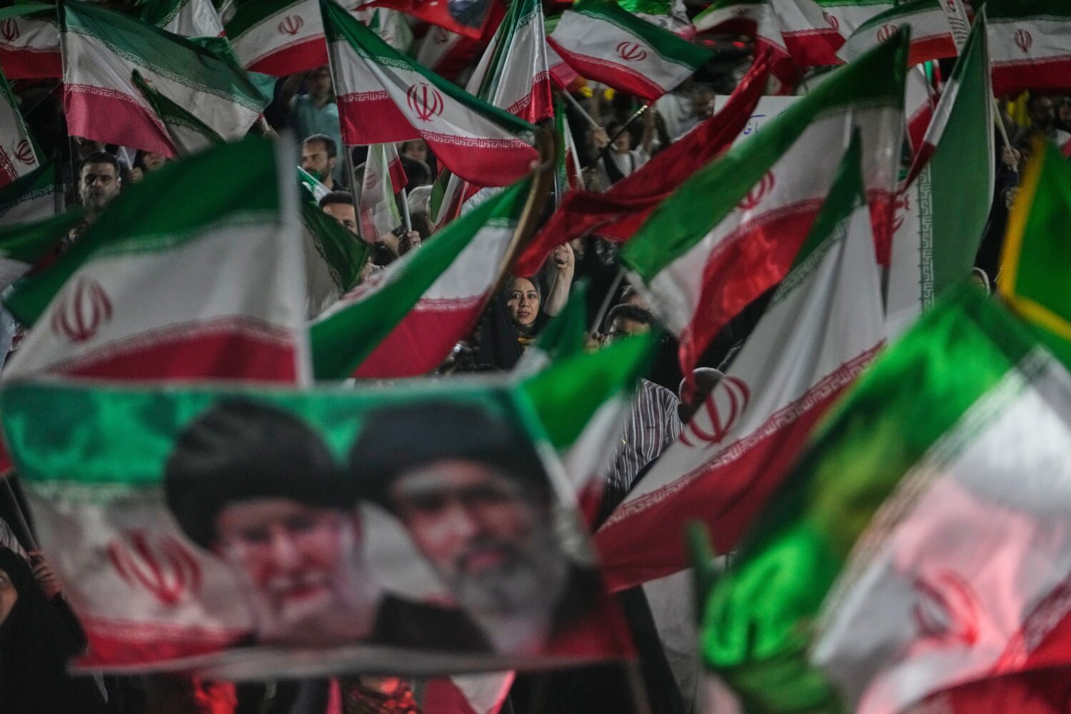 Pro-government Iranian demonstrators wave Iranian flags and a portrait of the Supreme Leader Ayatol...